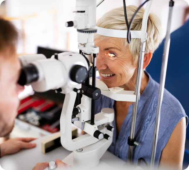 Eye‑care professional examining a patient with diagnostic equipment during a retinal exam.