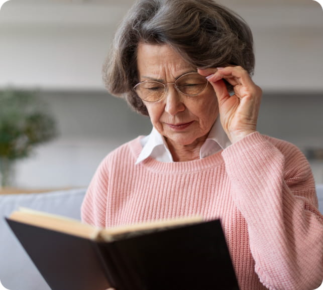 Older person squinting while reading, representing difficulty with near vision