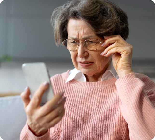 Older person looking at a phone and squinting, illustrating difficulty with vision and early symptoms