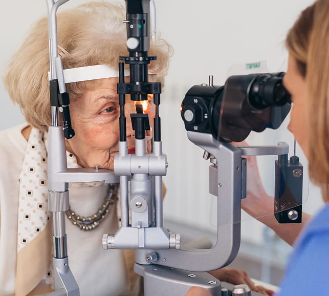Eye‑care professional examining a patient with diagnostic equipment during a follow‑up retinal check.